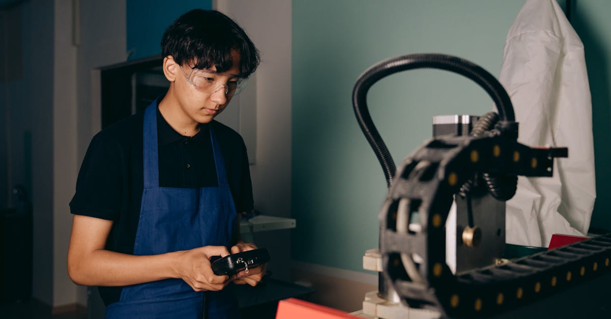 Young technician programming a robot via teach pendant